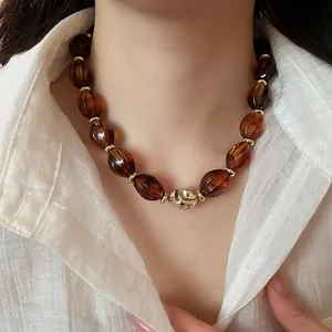 Close-up of amber acrylic twisted oval bead necklace on a model wearing white shirt