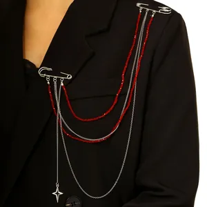 Detalle de broche con flecos de cuentas de cristal rojo y cadenas en una chaqueta negra