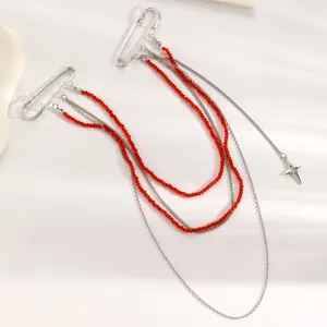 Dettaglio dell'accessorio spilla da balia a più strati con perline rosse e stella