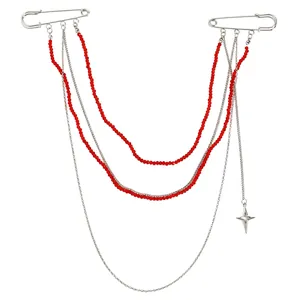 Vista detallada de un broche de cadenas plateadas multicapa con cuentas rojas y estrella
