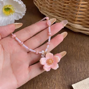 Elegant handmade pink flower pendant necklace with pastel beads on wooden surface