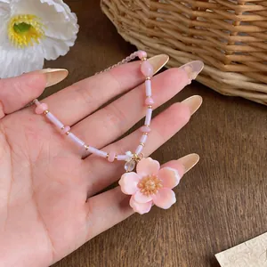 Elegant pink flower pendant necklace with beads shown on a hand close-up detail