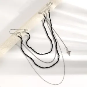 Dettaglio della spilla con catene di perline nere multistrato e ciondolo a stella per accessori moda