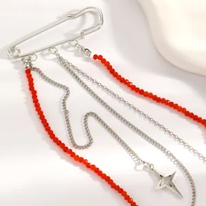 Dettaglio di spilla da balia argento con nappe di perline rosse e ciondolo a stella