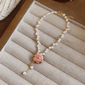 Elegant pearl necklace featuring a detailed pink rose pendant displayed in a tray