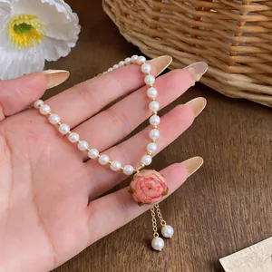 Detailed close-up showing a pink rose pendant on a dainty white pearl beaded necklace