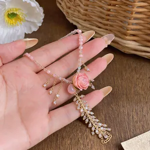 Close-up of elegant pink rose pendant necklace with crystal tassel detail