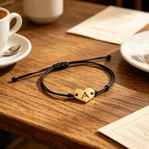 Detailed view of a gold-plated heart pendant with letter A on a black braided cord.