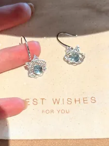 Detail van zee-blauwe glazen kralen oorbellen met zirkonia schelp op een geschenkzak.