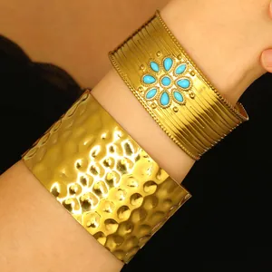 Vue détaillée de bracelets manchettes dorés martelés et turquoise portés sur le bras