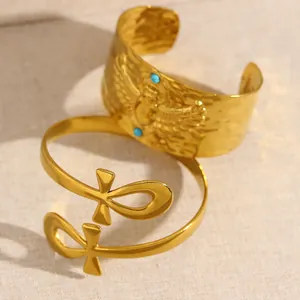 Détail macro de manchettes dorées en acier inoxydable avec motifs scarabée et croix ankh