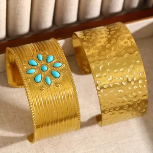 Vue détaillée de deux larges bracelets dorés avec texture martelée et pierres turquoise.