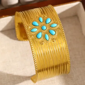 Vue détaillée d'un large bracelet manchette doré avec une fleur en pierres turquoises