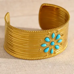 Vue rapprochée d'un large bracelet manchette en acier doré avec turquoises et texture martelée