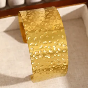 Gros plan sur la texture martelée d'un large bracelet manchette en acier inoxydable doré