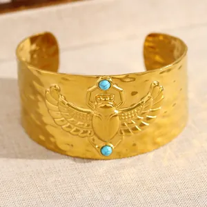 Détail d'un bracelet manchette doré scarabée égyptien avec turquoise et martelé