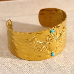 Vue détaillée d'un bracelet manchette doré martelé avec un motif de scarabée serti de turquoise