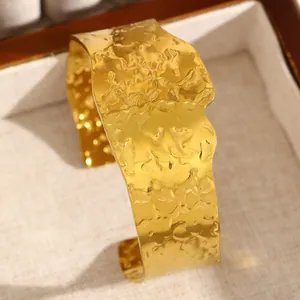 Vue détaillée d'un large bracelet manchette doré en acier inoxydable avec texture martelée