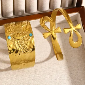Gros plan d'un bracelet manchette doré en acier avec scarabée et symbole de l'Ankh