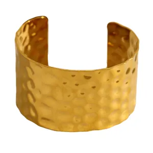 Gros plan d'un large bracelet manchette martelé doré en acier inoxydable.