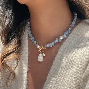 Detailansicht einer blauen Natursteinkette mit Perlen und goldenem OT-Verschluss am Model.