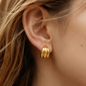 Detailed close-up showing triple-banded gold C-shaped hoop earrings on a model ear.