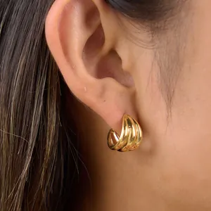 Close-up view of a gold multi-layered C-shaped earring on an ear, stainless steel jewelry
