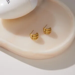 Detailed close-up of gold-plated C-shaped stainless steel earrings with ribbed texture
