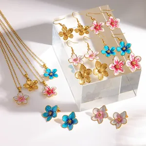 Detail shot of 18k gold plated enamel flower earrings and necklaces on clear stand.