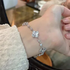 Detail view of a sparkling zircon clover pendant bracelet worn on a wrist for elegant style