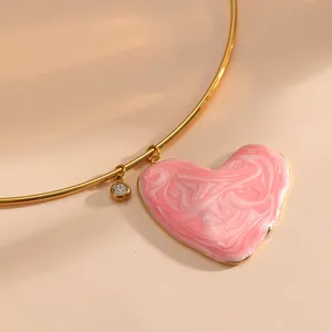 Gros plan d'un pendentif cœur rose marbré avec bordure dorée sur collier inox