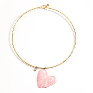 Détail du pendentif cœur en émail marbré rose sur un tour de cou en acier inoxydable doré