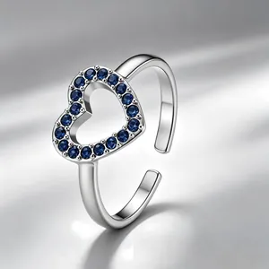 Gedetailleerde close-up van een zilveren hartring met fonkelende blauwe zirkonia stenen