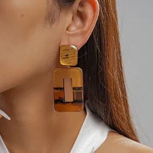 Λεπτομέρεια από γεωμετρικά σκουλαρίκια από κεχριμπαρένια ρητίνη σε Ασιάτισσα μοντέλο