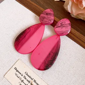 Detailansicht der rosa marmorierten Harz-Ohrringe in Tropfenform mit Tusche-Effekt.