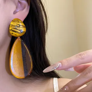 Detailansicht eines marmorierten Harz-Ohrrings mit elegantem braun-goldenem Muster