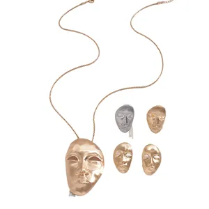 Artistic avant-garde metallic human face mask pendant necklace set in multiple metal finishes