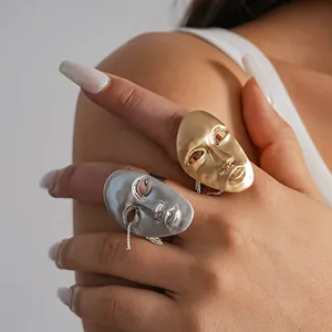 Detailed view of unique gold and silver artistic human face mask rings with metallic finish