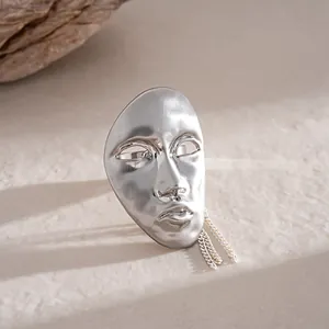 Detail showing the intricate human mask pendant with tassel chain in silver finish.