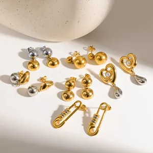 Detailed view of two-tone stainless steel earrings in gold and silver sphere and heart shapes.