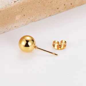 Primo piano di un orecchino a sfera minimalista in acciaio inossidabile dorato e chiusura.