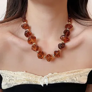 Collier en perles d'acrylique ambrées irrégulières avec accents dorés porté par un modèle