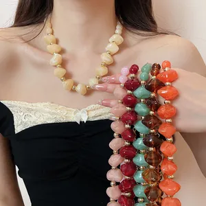Vue détaillée de colliers de perles en acrylique colorées portés par un modèle.