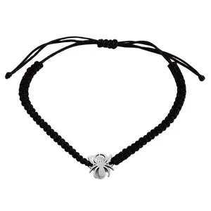 Macro shot of a black woven adjustable bracelet featuring a silver spider charm detail.