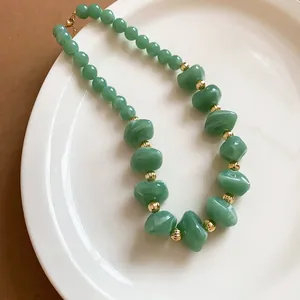 Détail des perles acryliques vertes et des entretoises dorées sur un collier élégant