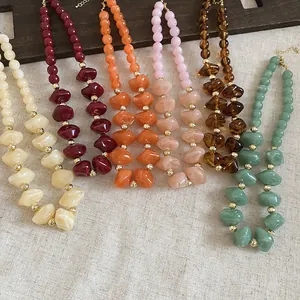 Vue détaillée de colliers de perles en acrylique colorées avec perles dorées élégantes.