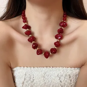 Détail d'un collier de perles en acrylique rouge porté par un mannequin féminin