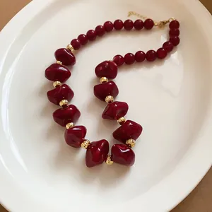 Vue macro des perles en acrylique rouge irrégulières et des perles d'espacement dorées