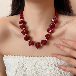 Collier élégant en perles d'acrylique bordeaux avec entretoises dorées sur modèle