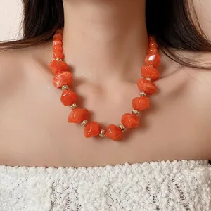 Gros plan d'un collier de perles acryliques orange à texture marbrée
